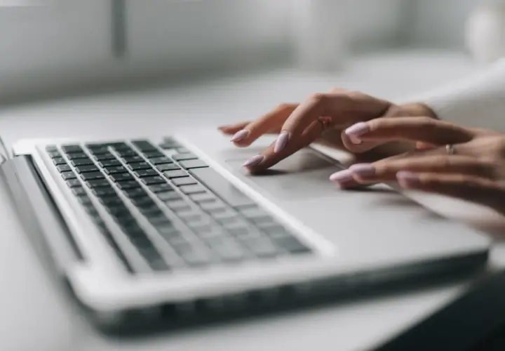 Dłonie z różowym lakierem na paznokciach pracują na touchpadzie laptopa. To efekt pracy nad projektem, który wymaga precyzji, jak druk sd-3.