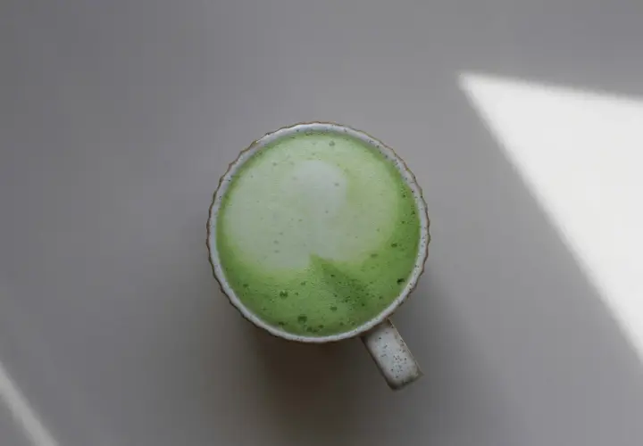 Eine Tasse cremiger Matcha-Latte, die die positive matcha wirkung psyche auf ruhige Weise unterstreicht.