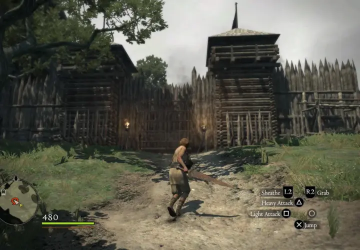 Postać w grze Dragon's Dogma 1 zbliża się do drewnianej bramy warownej.