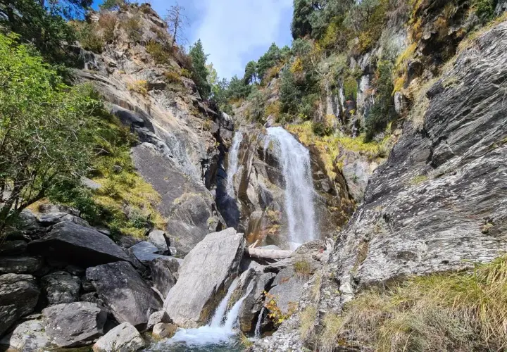 Cascada imponente en la ruta Rupit, rodeada de rocas y vegetación otoñal. El agua cae con fuerza sobre las piedras, creando un paisaje natural espectacular.