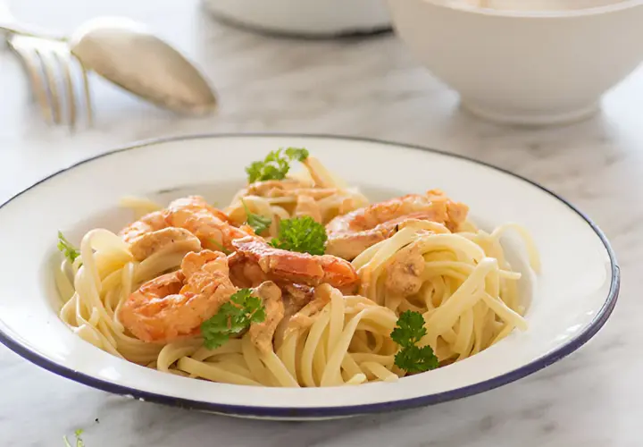 Pasta con jugosa salsa de langostinos, coronada con perejil fresco. Un plato delicioso y fácil de preparar.