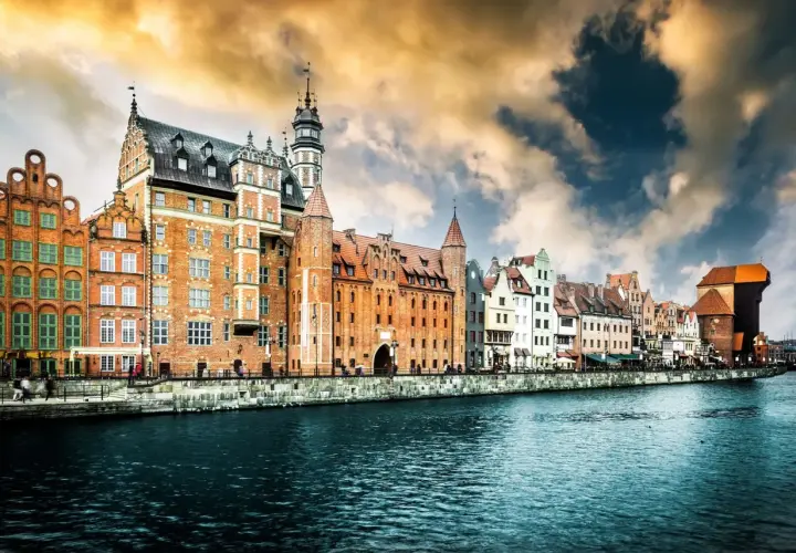 Malownicze kamienice nad Motławą, symbol gdańsk stare miasto, pod burzowym, złocistym niebem.