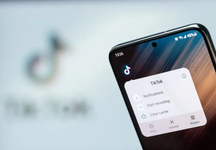Telefon z aplikacją TikTok, gdzie widać opcję "Clear cache" (wyczyść pamięć podręczną), by przyspieszyć działanie.