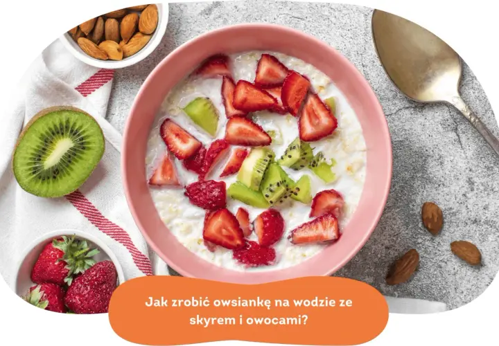 Pyszna owsianka z owocami: truskawkami i kiwi, podana w różowej miseczce. Obok migdały i łyżka.