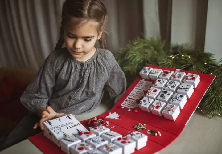 Niña prepara su calendario de adviento, una manualidad navideña para contar los días.