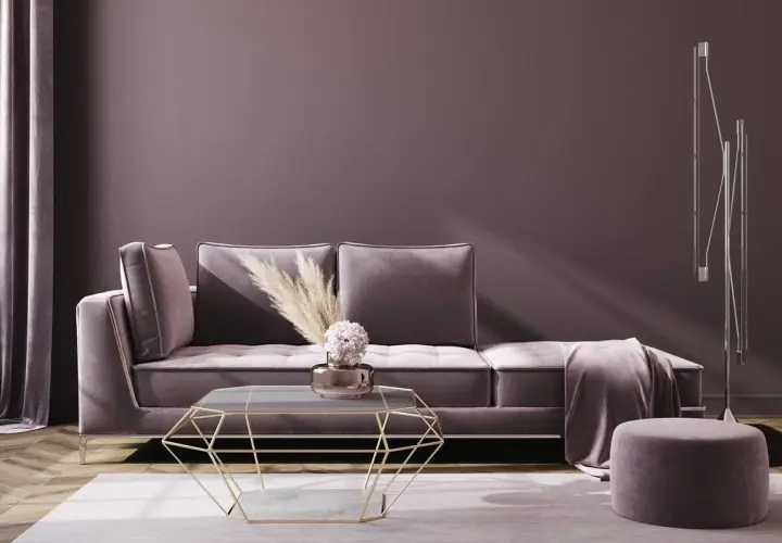 Ein luxuriöses Wohnzimmer in mauve farbe mit einem Samtsofa, einem geometrischen Couchtisch und einem Hocker.