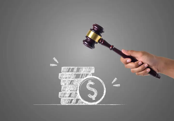 Marteau d'un juge au-dessus d'une pile de pièces dessinées, symbolisant une vente aux enchères où le propriétaire ne part pas.