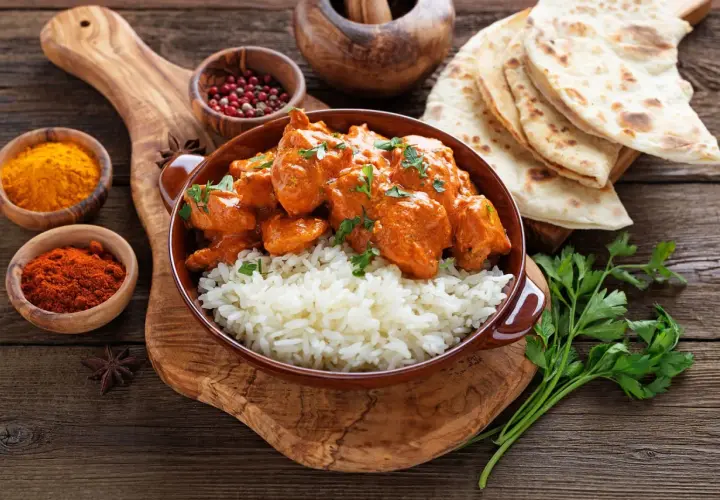 Aksamitny kurczak tikka masala z ryżem basmati, podany z plackami naan i aromatycznymi przyprawami.