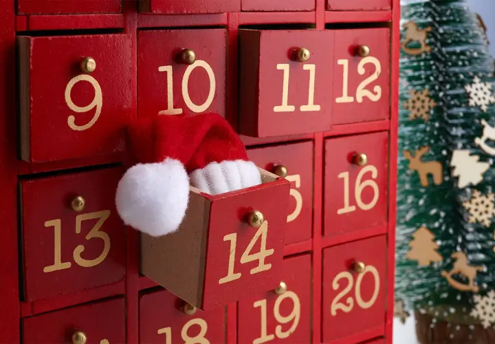 Un calendario dell'Avvento rosso con cassetti numerati. Il cassetto 11 è aperto, mostrando un cappellino di Babbo Natale. Ideale per idee su cosa mettere nel calendario avvento.