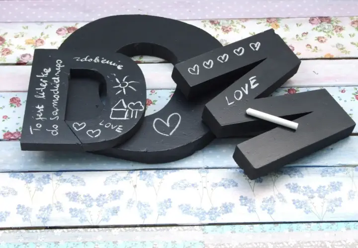 Czarna litera "D" z napisem "To jest literka do samodzielnego..." i rysunkami. Obok litery "N" z napisem "LOVE" i serduszkami, wykonane w stylu pismo kaligraficzne.