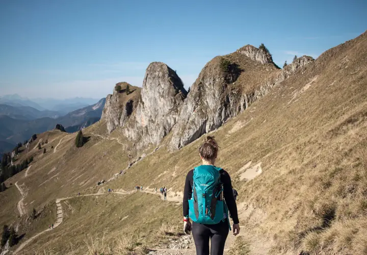 Wanderin auf einem Pfad in den beeindruckenden Berge in Bayern. Die Sonne scheint, der Himmel ist blau.
