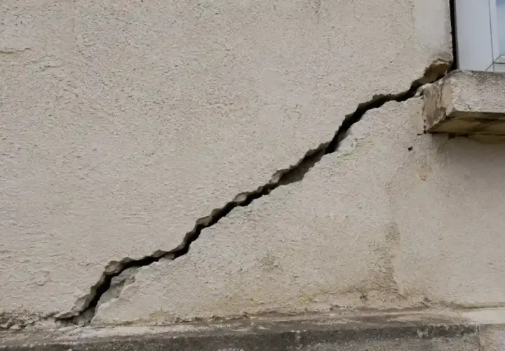 Une fissure importante traverse la façade d'un bâtiment, nécessitant une réparation urgente.