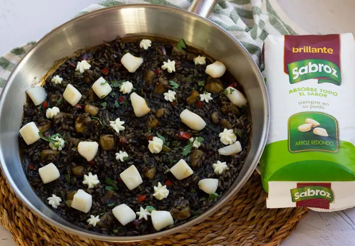 Arroz negro con sepia, adornado con trozos de sepia y puntos de alioli, listo para ser cocinado con arroz redondo Sabroz.