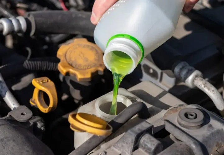 Se vierte líquido verde brillante en el depósito del coche. Esto demuestra para qué sirve el anticongelante del coche: mantener el motor a la temperatura adecuada.