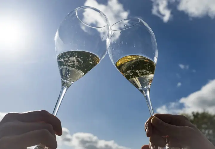 Deux flûtes de champagne pétillant levées en l'air, sous un ciel bleu éclatant. Un toast à Épernay !