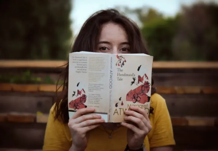 Dziewczyna w żółtej bluzce czyta książkę po angielsku "The Handmaid's Tale" Margaret Atwood.