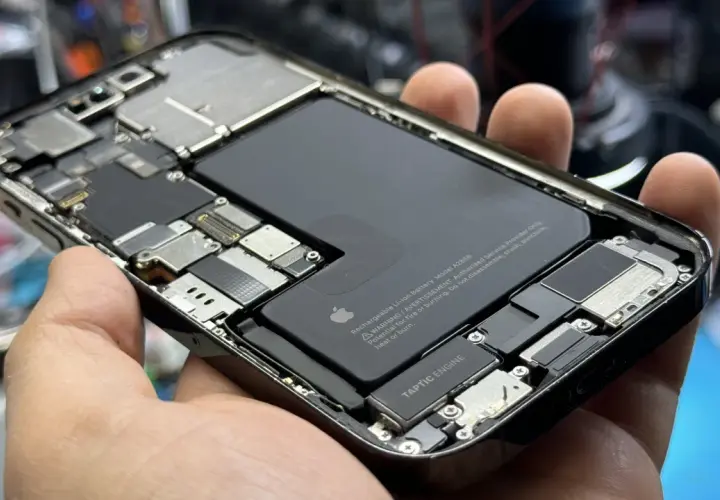 Wnętrze iPhone'a z widoczną baterią i elementami płyty głównej. Czas sprawdz port ładowania USB.