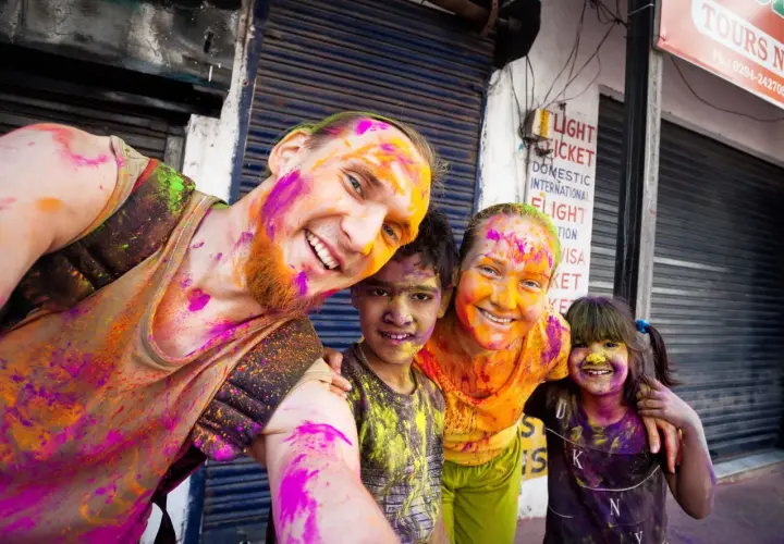 Fröhliche Familie feiert das Holi Festival in Indien, Gesichter und Kleidung bunt mit Pulverfarben bespritzt.