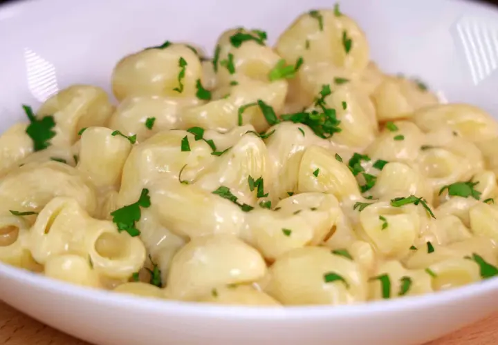 Mac and cheese cremoso, con trozos de perejil fresco espolvoreados. Un plato reconfortante y delicioso.