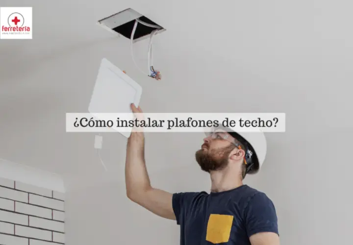 Hombre instalando bombillas plafon de techo, con casco y gafas de seguridad.