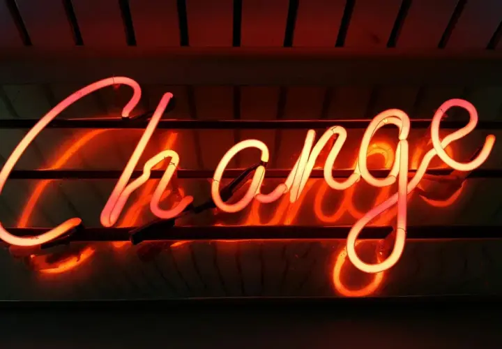 Néon rougeoyant "Change" pour illustrer comment changer de syndic en 5 étapes.