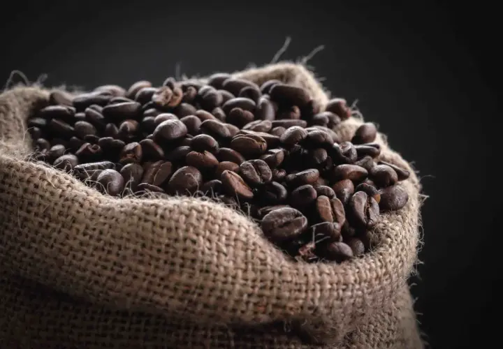 Un saco de arpillera lleno de granos de café tostados, una fuente natural de cafeína para el pelo.
