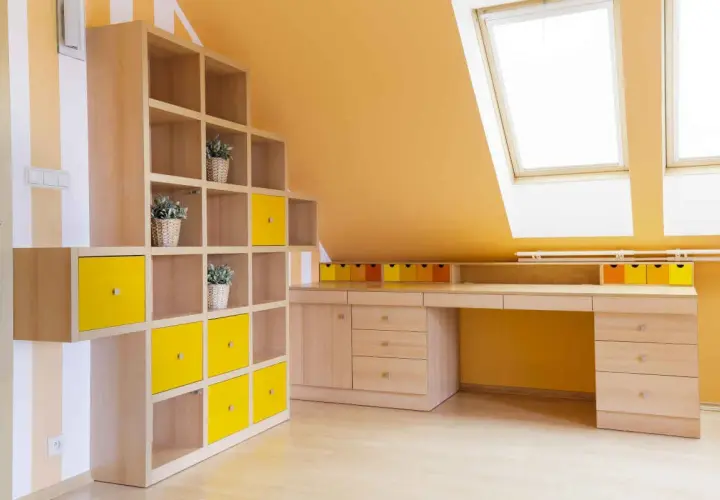 Colori vivaci per le pareti di una mansarda: arancione acceso e tocchi di giallo su una libreria modulare.