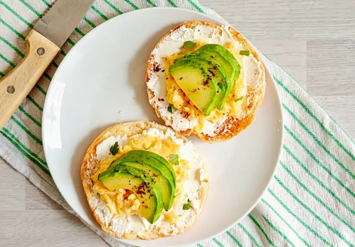 Deux toasts avec fromage frais, œufs brouillés et avocat. Un petit-déjeuner sain et savoureux, idéal pour maîtriser les calories.