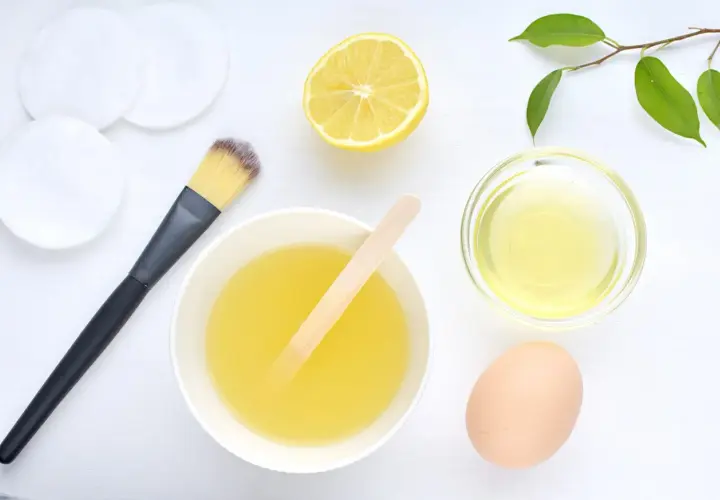 Ingredientes para una mascarilla de huevo para el pelo: huevo, limón, aceite y brocha.