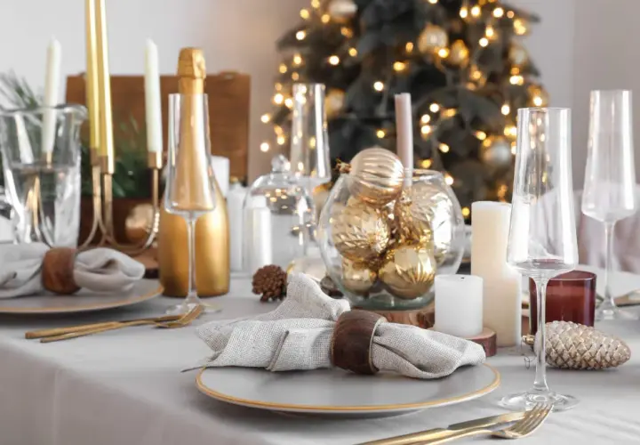 Festlich gedeckter Tisch Weihnachten mit goldenen Kugeln, Kerzen und Champagner. Ein eleganter Blickfang für die Feiertage.
