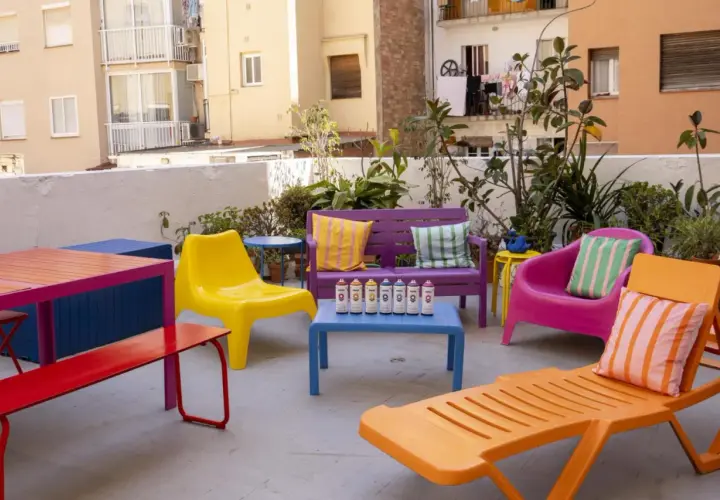 Un colorido conjunto de muebles de terraza, listo para pintar. Sillas, bancos y mesas en vibrantes tonos, con latas de spray dispuestas para dar vida a este espacio exterior.