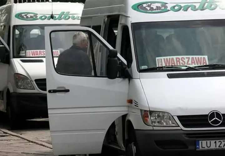 Białe busy Contbus z napisem "WARSZAWA" na przedniej szybie, jeden z otwartymi drzwiami.