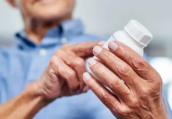 Ältere Hände halten eine Pillendose. Die Glucosamin Wirkung für Gelenke wird hier thematisiert.