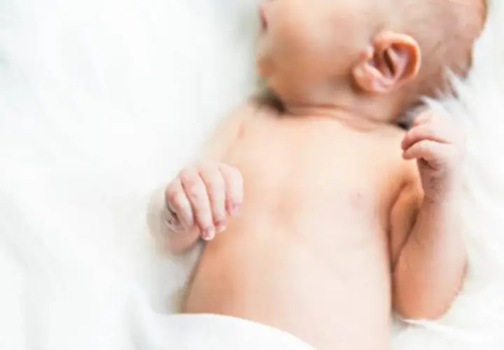 Delikatna skóra niemowlęcia, być może zmagającego się z trądzikiem niemowlęcym lub skazą białkową, na białym tle.