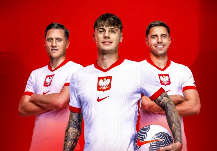 Trzech uśmiechniętych piłkarzy reprezentacji Polski w białych koszulkach z godłem orła. Jeden z nich trzyma piłkę.