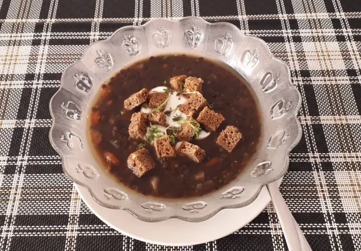 Gęsta, aromatyczna zupa z czarnej soczewicy, udekorowana grzankami i kleksem śmietany. Idealna na chłodne dni.