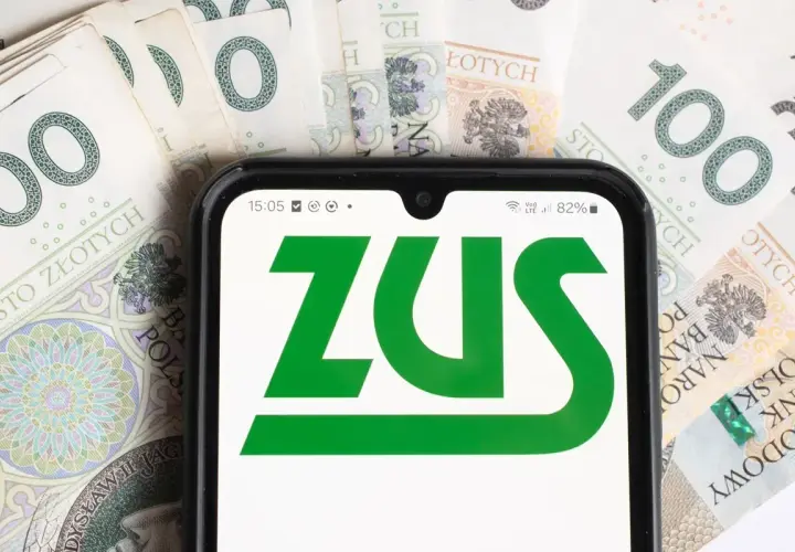 Telefon z logo ZUS na tle banknotów 100 zł. To symbol współpracy i finansów.