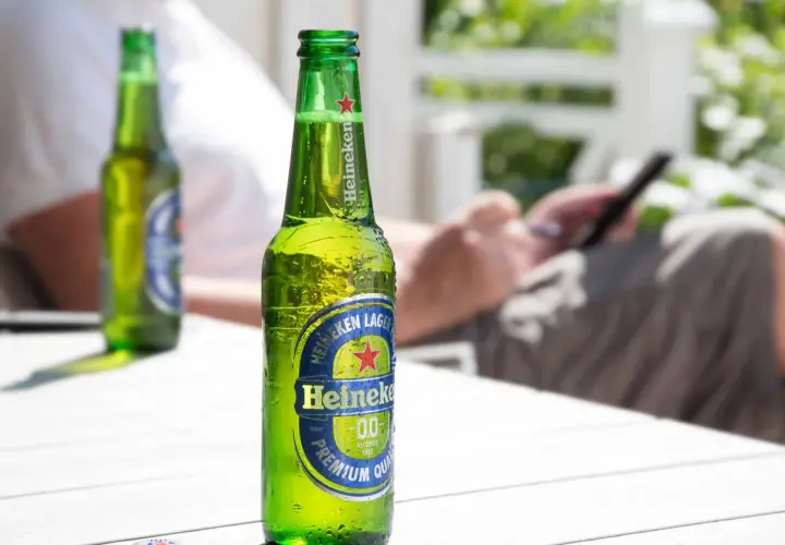 Chłodne piwo Heineken 0.0 na stole. Zastanawiasz się, ile węglowodanów ma piwo? To piwo jest bezalkoholowe.