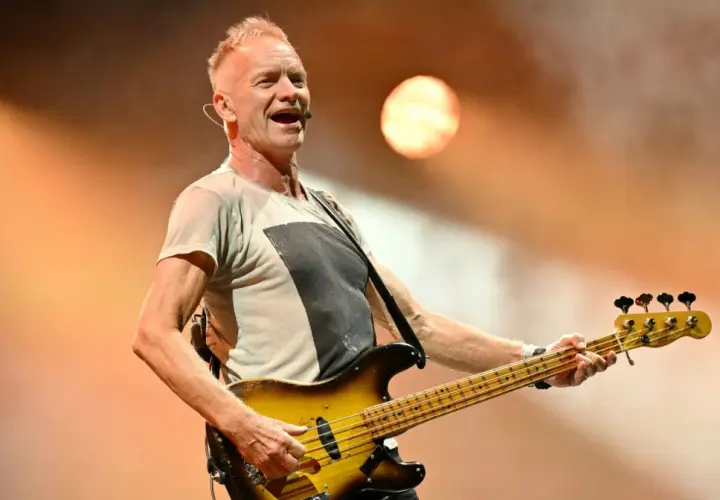 Wokalista The Police, Sting, gra na gitarze basowej podczas koncertu.
