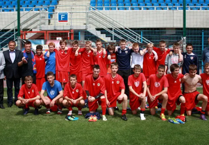 Piast Gliwice zawodnicy w czerwonych strojach pozują do zdjęcia na boisku.