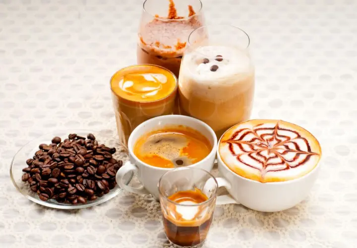 Różnorodne kawy, w tym latte z wzorem, espresso i napoje mrożone, idealne na keto dietę. Obok ziarna kawy.