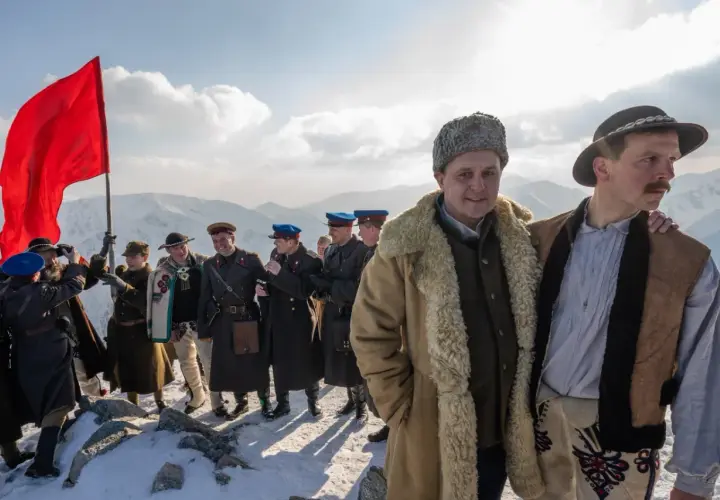 Grupa ludzi w strojach historycznych na tle gór. Czerwona flaga powiewa na wietrze. To może być scena z filmu, która zasługuje na biała odwaga recenzja.