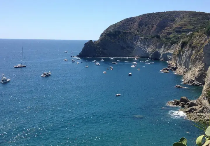 Baie de Sant'Angelo à Ischia, parsemée de bateaux sous un ciel bleu éclatant.