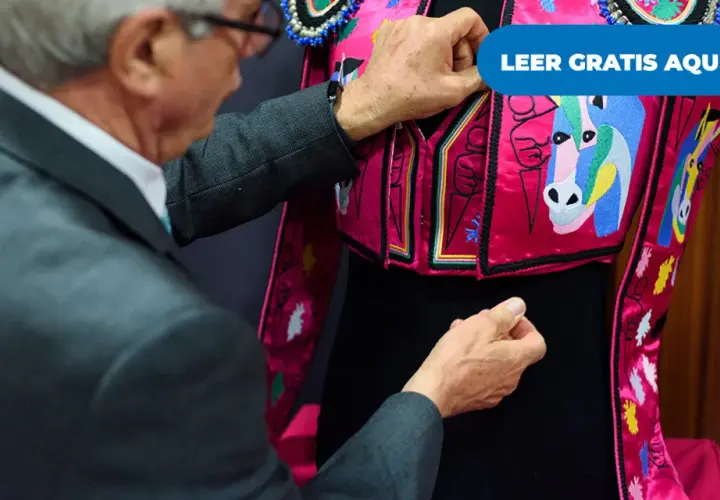Un hombre ajusta un traje de luces rosa con caballos bordados, listo para una corrida en Madrid.