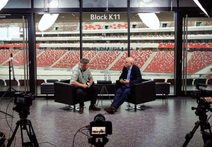 Tomasz Tomaszewski rozmawia z mężczyzną na tle stadionu.