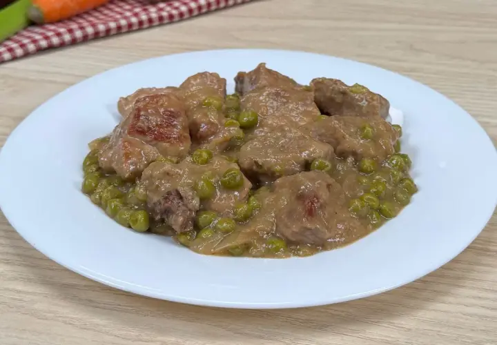 Un saporito spezzatino con piselli, servito su un piatto bianco, pronto per essere gustato.