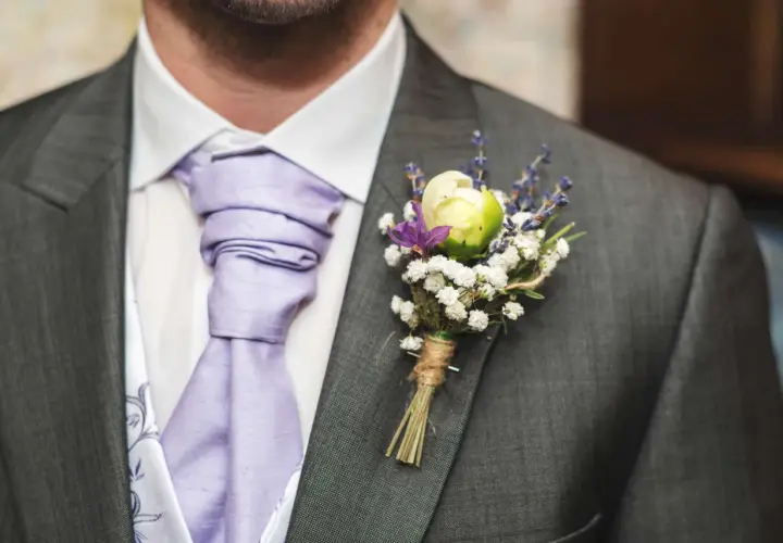 Elegancka butonierka co to? To ozdoba z kwiatów i lawendy przypięta do marynarki.