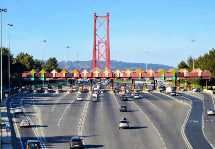 Korkociąg samochodów na autostradach Portugalii, zbliżających się do bramki opłat pod czerwonym mostem.