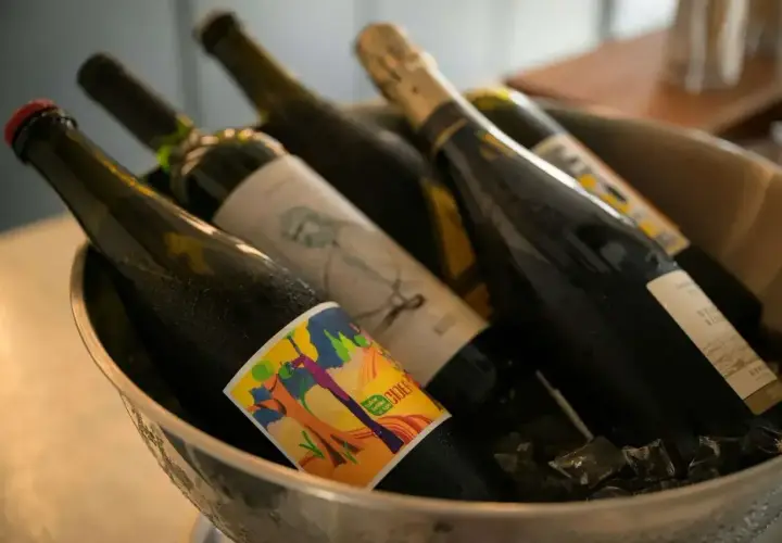 Butelki z winem w wiaderku z lodem. Zastanawiasz się, czy można przewozić alkohol w bagażu rejestrowanym? Sprawdź przepisy!
