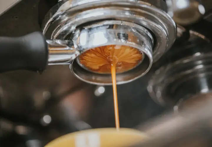Espresso spływa do filiżanki, przygotowując americano. Dowiedz się, ile kofeiny ma americano.